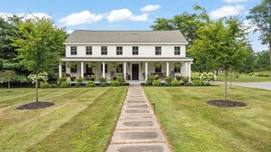 A two-story house with a front porch, a stone pathway leading to the entrance, and a well-maintained lawn. - Farmhouse at Leeds by Avantstay Walled Garden + Soaking Tub + Private Barn Near Hudson (Leeds)