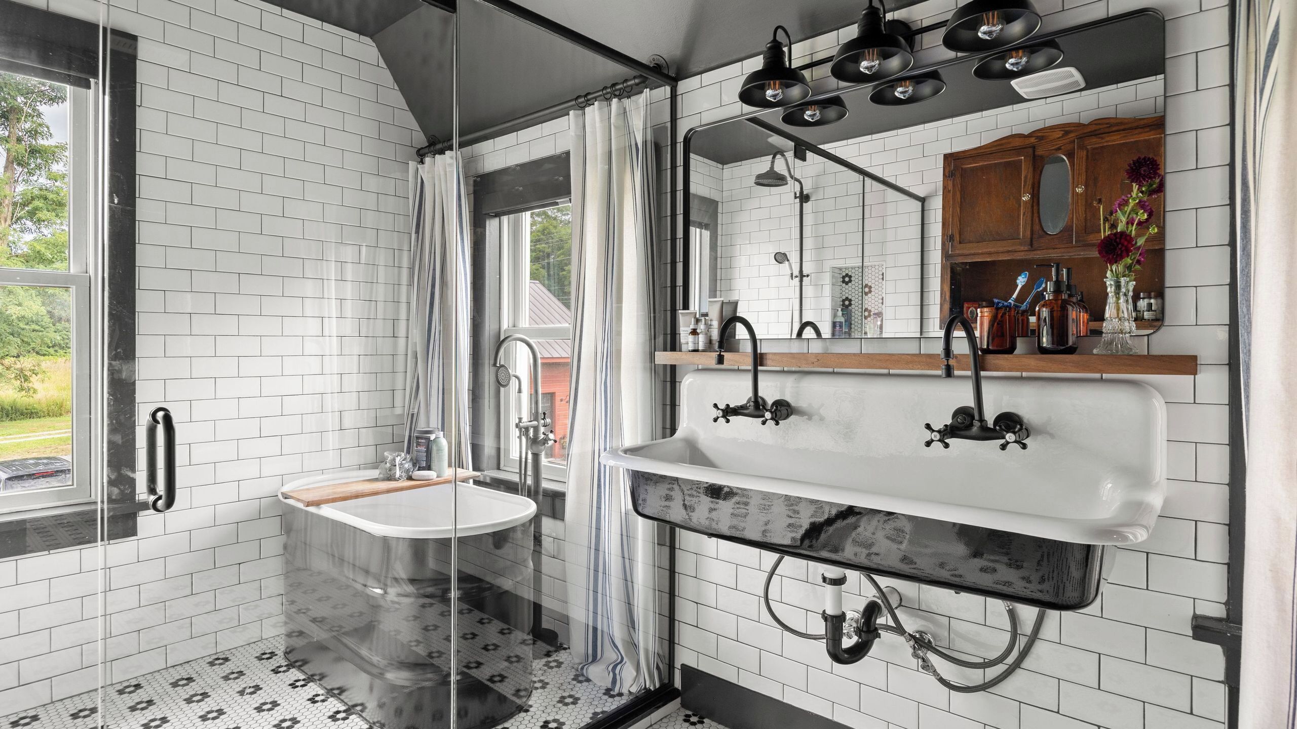 Ein modernes Badezimmer mit einer Duschkabine aus Glas, einem weißen Waschbecken mit Holzablage und einem großen Spiegel darüber.