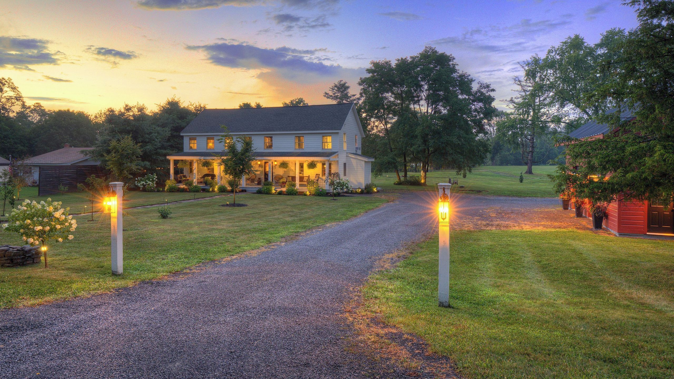 A two-story house with a porch, a gravel driveway, and a well-maintained lawn.