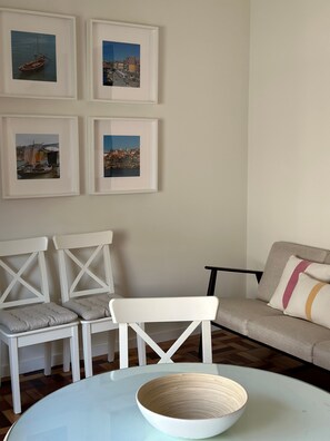 A room with a round table, two white chairs, a sofa, and four framed pictures on the wall. - Apartment in the heart of Porto (Porto)