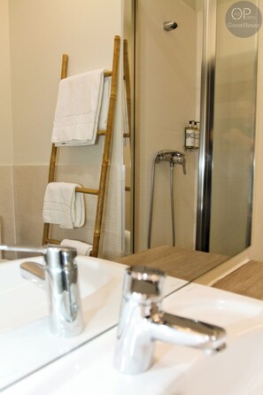 A bathroom with a shower, a wooden towel rack, and a mirror reflecting the room. - Apartment in the heart of Porto (Porto)