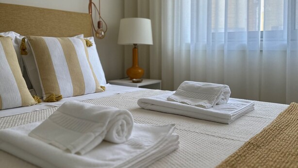 Een opgemaakt bed met kussens, een lamp en handdoeken in een hotelkamer.