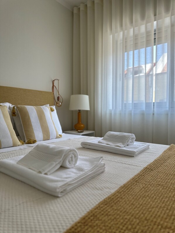 A neatly made bed with pillows, a lamp, and towels on a hotel room. - Apartment in the heart of Porto (Porto)