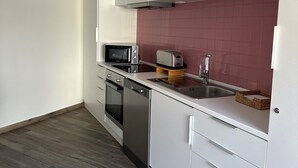 Een moderne keuken met witte kastjes, een magnetron, broodrooster en vaatwasser.