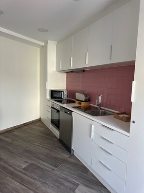 A modern kitchen with white cabinets, a microwave, toaster, and dishwasher. - Apartment in the heart of Porto (Porto)