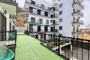 A multi-story residential building with balconies, a green artificial lawn, and a view of the surrounding area. - Dog-friendly Hotel Suite With Ocean-view Rooftop Infinity Pool, Central AC & gym (Cabo San Lucas)