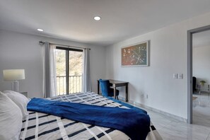 A modern hotel room with a large bed, a desk, a chair, and a view through a window. - Dog-friendly Hotel Suite With Ocean-view Rooftop Infinity Pool, Central AC & gym (Cabo San Lucas)