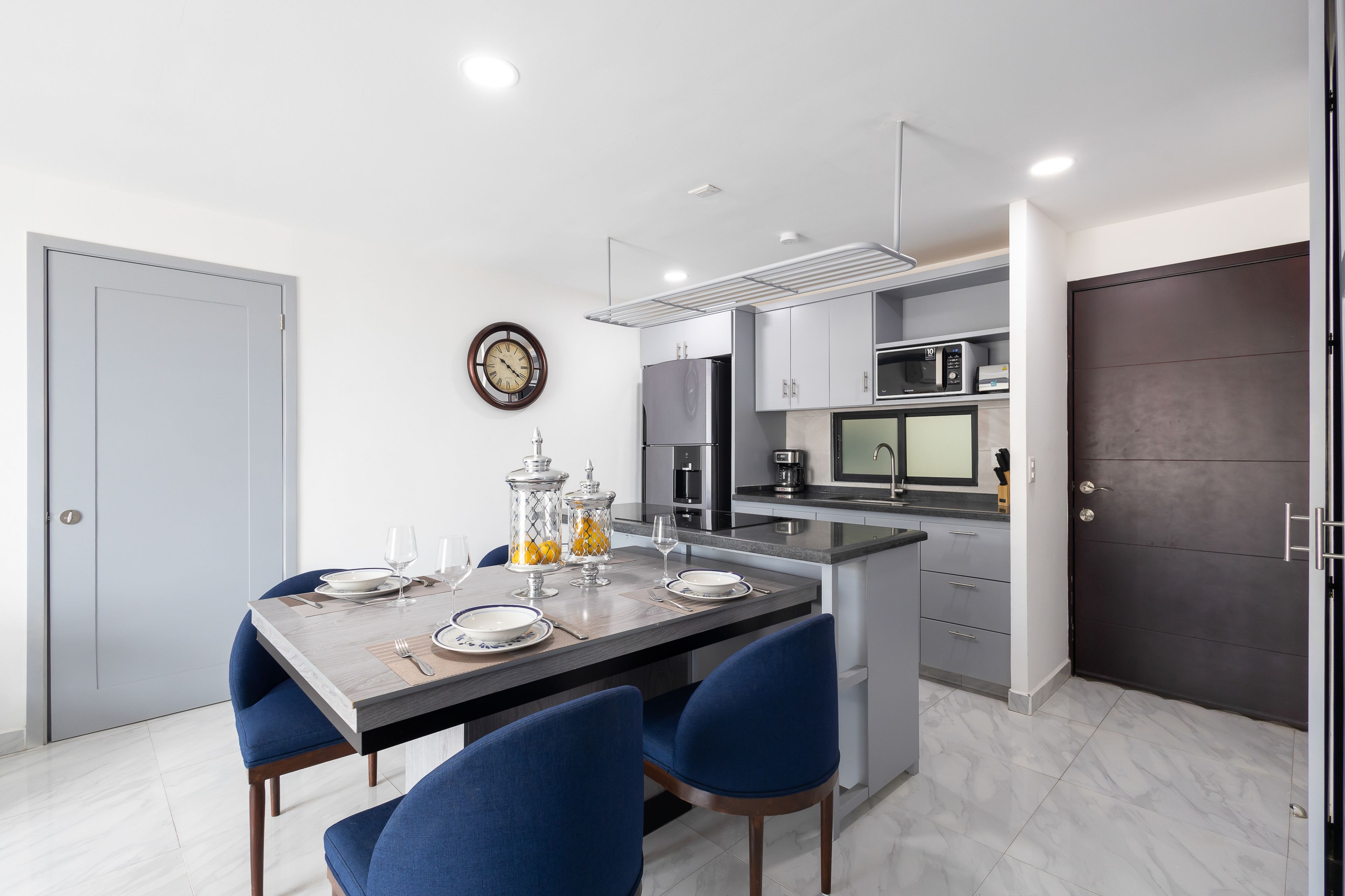 Una cocina moderna con comedor, que cuenta con una isla grande, electrodomésticos integrados y un reloj en la pared.