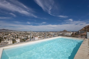 A rooftop pool with a cityscape view, a clear sky, and distant hills. - Dog-friendly Hotel Suite With Ocean-view Rooftop Infinity Pool, Central AC & gym (Cabo San Lucas)