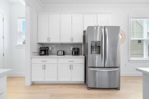A modern kitchen with white cabinetry, a stainless steel refrigerator, and a toaster. - Sandy Cheeks | Pet-Friendly + Pool + Putting Green (Orange Beach)