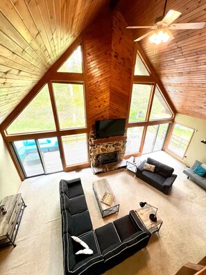 Ein geräumiges Loft mit Kamin aus Stein, großen Fenstern und Deckenventilator.