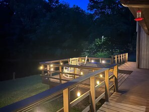 Eine Holzterrasse mit Glasumrandung, Lichterketten und einem Stuhl.