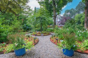 Ein Gartenweg, umgeben von verschiedenen Pflanzen und Bäumen.