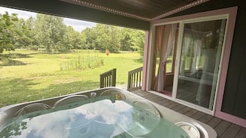 Boblebad på en træterrasse med udsigt over en græsplæne og træer.