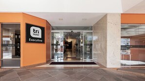 L'ingresso di un hotel con una porta in vetro, un cartello con la scritta 'TRI Hotel Executive' e un pavimento piastrellato.