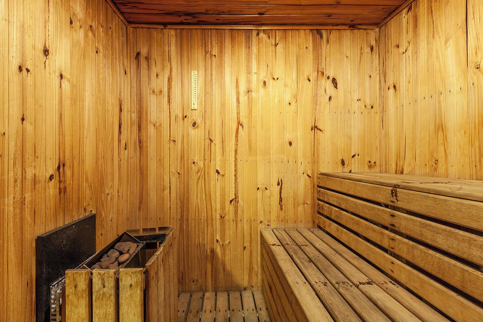 Una sauna con paredes de madera, un banco y un calentador.