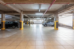 An underground parking garage with multiple levels, concrete pillars, and tiled floors.