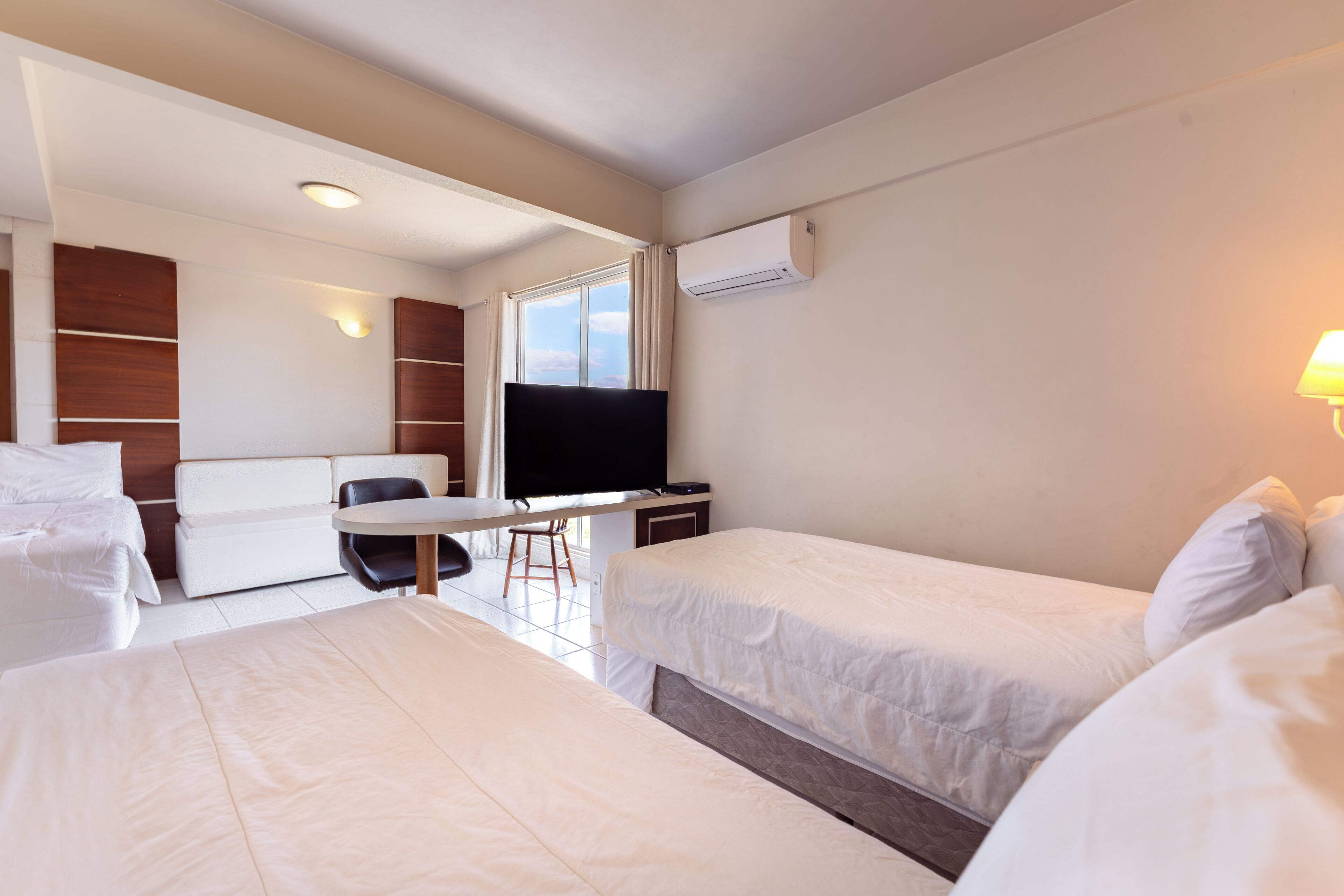 Hotellihuone, jossa on kaksi sänkyä, työpöytä, tuoli, televisio ja ilmastointilaite.