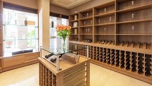 Una cantina vinicola con scaffali di legno e un tavolo vetrina con un vaso di fiori.