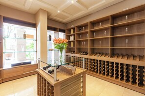 A wine cellar with wooden shelves and a glass display table with a vase of flowers. - TRI HOTEL EXECUTIVE SANTA MARIA (Santa Maria)