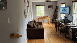 Un amplio espacio de sala con piso de madera, un sofá, una mesita de centro y un televisor.