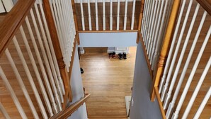Una escalera de madera con barandillas blancas que conduce a un rellano donde hay zapatos.