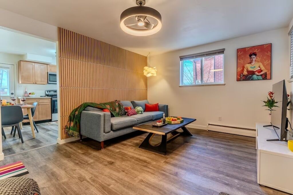 A modern living room with a sofa, coffee table, and a dining area with chairs.