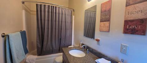A bathroom with a shower curtain, a sink, a mirror, and a towel rack.