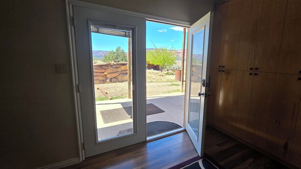Quarto com porta de vidro deslizante para área externa, armário de madeira e porta com puxador de metal.