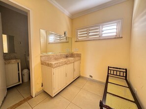 Un baño con lavamanos, espejo y ventana.