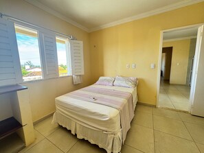 Un dormitorio con cama, ventana con contraventanas y vistas al exterior.