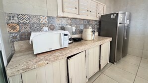 A kitchen with a microwave, toaster, kettle, and refrigerator. - Recanto Renascer (Aquiraz)