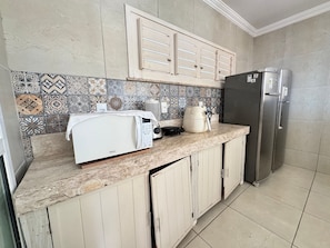 A kitchen with a microwave, toaster, kettle, and refrigerator. - Recanto Renascer (Aquiraz)