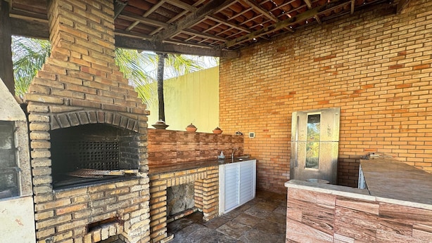 An outdoor kitchen with a brick oven, a sink, and a cabinet. - Recanto Renascer (Aquiraz)