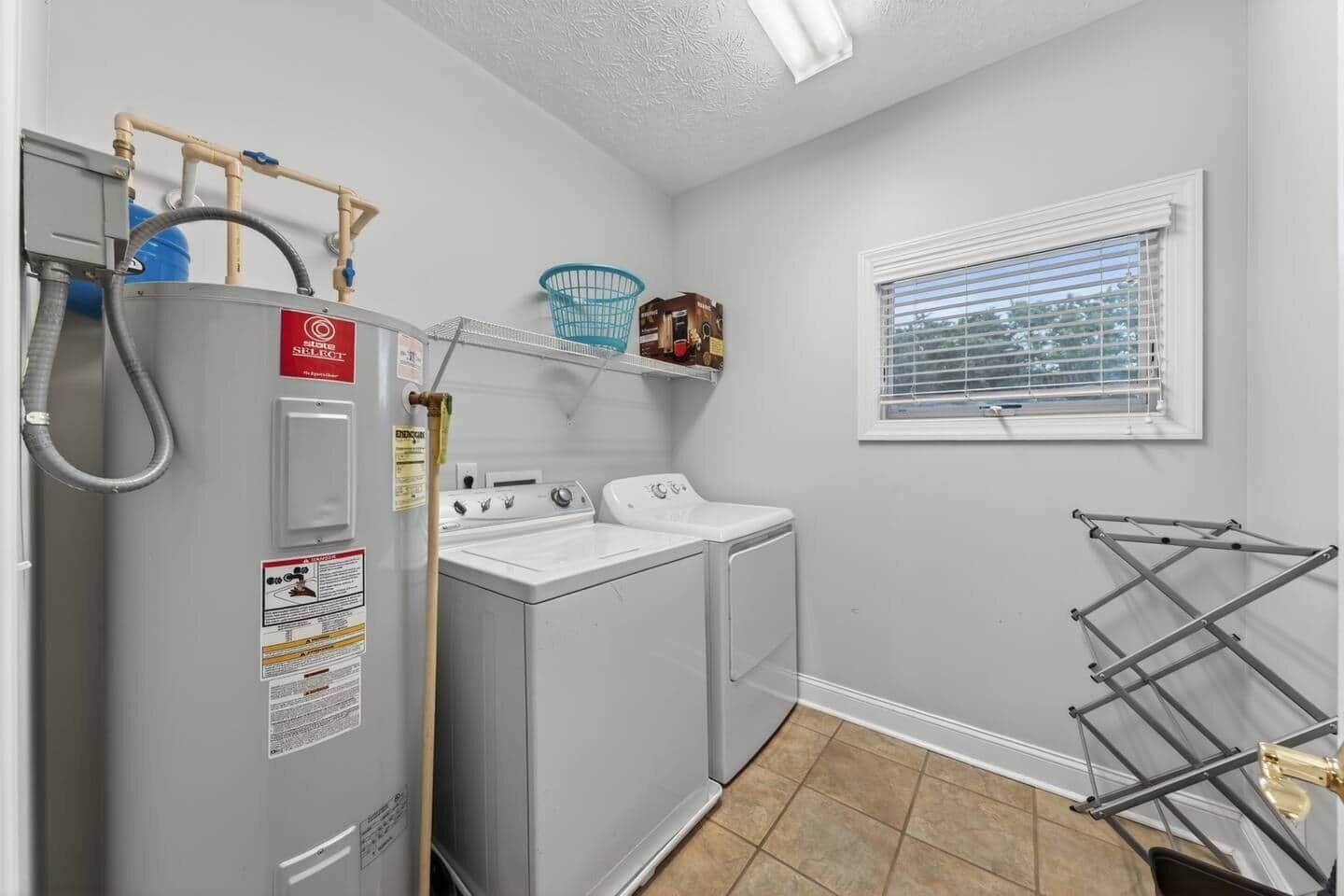 A laundry room with a washing machine, dryer, and a drying rack.