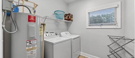 A laundry room with a washing machine, dryer, and a drying rack.
