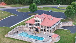 Un edifici gran amb piscina, un porxo cobert i un aparcament.