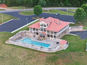 A large building with a swimming pool, a covered patio, and a parking lot.