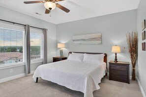 A bedroom with a bed, two bedside tables, a ceiling fan, a window with blinds, and a wall-mounted painting. - Siesta Sunset Retreat in Bridgewater Bay (Bedford County)