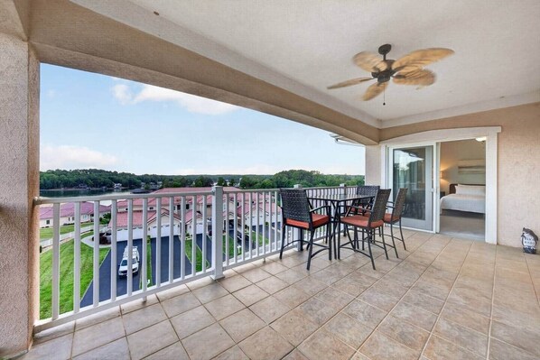 A balcony with a view of a residential area, a ceiling fan, and a table with chairs. - Siesta Sunset Retreat in Bridgewater Bay (Bedford County)