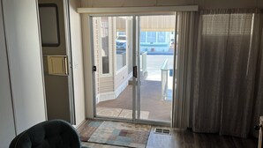 Una habitación con puerta corrediza de vidrio que da a un balcón, una silla y un tapete estampado.