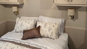 Un dormitorio con una cama, dos mesitas de noche, un aparador y una estantería con fotos enmarcadas.
