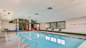 Ein Innenpool mit klarem Wasser, umgeben von Liegestühlen und einer kleinen Sitzecke.