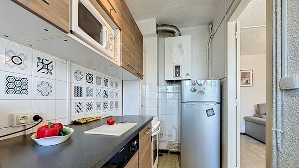 A modern kitchen with a built-in dishwasher, a stainless steel refrigerator, and a variety of patterned tiles on the backsplash. - California by Interhome (Le Grau du Roi)