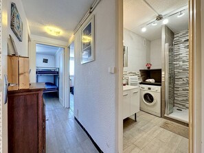 A corridor leading to a room with bunk beds, a washing machine, and a shower. - California by Interhome (Le Grau du Roi)
