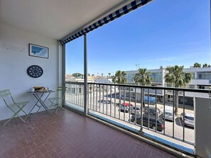 Een balkon met uitzicht op een parkeerplaats en gebouwen.