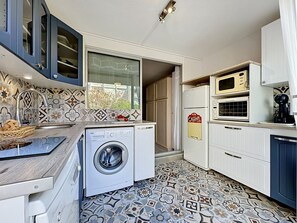 Eine kleine Küche mit Waschmaschine, Mikrowelle und Kaffeemaschine.