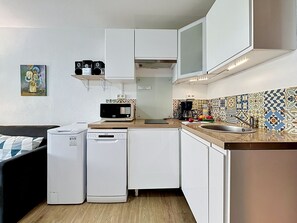 A compact kitchen with a microwave, coffee maker, and a small sink. - Les Floralies II by Interhome (Le Grau du Roi)
