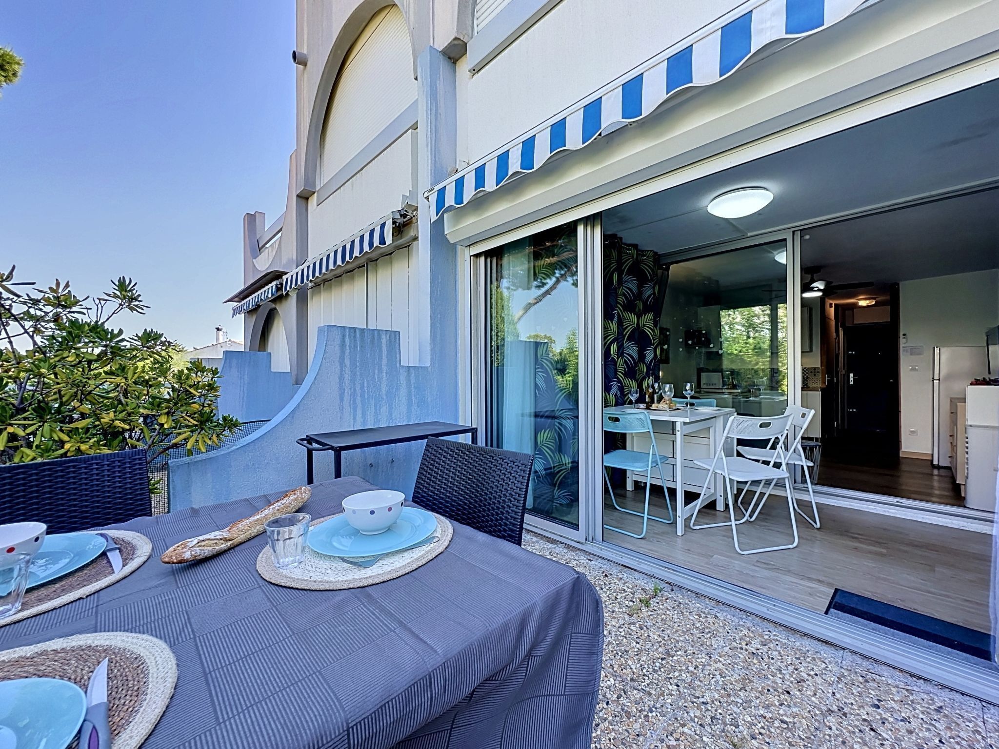 An outdoor dining area with a table, chairs, and a view into the building.