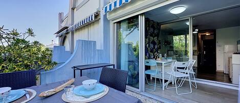 An outdoor dining area with a table, chairs, and a view into the building.